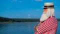 Elderly gray-haired man with a beard in a striped bathing suit and hat posing on the beach. Senior citizen on vacation Royalty Free Stock Photo