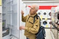 Elderly man choosing refrigerator in showroom of electrical appliance store Royalty Free Stock Photo