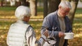 Elderly grey-haired volunteer woman helps out the charity organization by sharing her homemade soup with homeless people