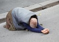 Elderly gypsy woman begging for passersby kneeling with her hand Royalty Free Stock Photo