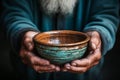 Elderly hands hold empty bowl, selective focus revealing stark hunger and destitution