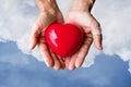 Elderly hands with wound holding red heart heart on blue sky and white clouds Royalty Free Stock Photo