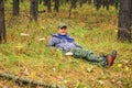 An elderly handsome man lies in an autumn pine forest