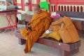 Elderly handsome traveler buddhist monk wearing traditional ceremonial orange robe with bulky luggage sitting on bench