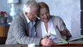 Elderly happy couple looking old photo album and smiling Royalty Free Stock Photo