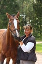 Elderly happy woman and brown horse in the forest Royalty Free Stock Photo