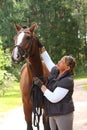 Elderly happy woman and brown horse in the forest Royalty Free Stock Photo