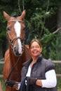 Elderly happy woman and brown horse in the forest Royalty Free Stock Photo