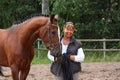 Elderly happy woman and brown horse in the forest Royalty Free Stock Photo