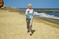 Elderly happy woman running on the beach along the coast near sea