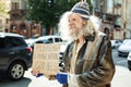Elderly hippy man begging for help standing near traffic jam