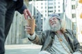 Elderly hippy man sitting on the street asking for money