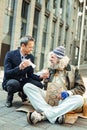 Elderly hippy wearing bright cap receiving food from stranger