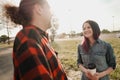 An elderly hipster man with long hair and a beard in a red plaid shirt is talking to a young woman. Summer warm evening Royalty Free Stock Photo