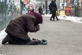 An elderly, homeless woman asks for mercy from indifferent passers-by. The concept of poverty, indifference, loneliness.
