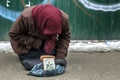 An elderly, homeless woman asks for mercy from indifferent passers-by. The concept of poverty, indifference, loneliness.