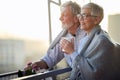 An elderly hugged couple in love is enjoying a view on the city from the terrace of their apartment at a beautiful sunset. Royalty Free Stock Photo