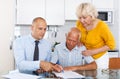 Elderly husband and wife signing agreement papers with bank worker