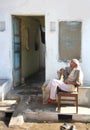 Elderly Indian man sits outside his home