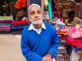 An elderly Indian shopkeeper sitting outside his store