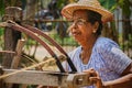 An elderly Indian woman making coconut ropes