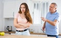 Elderly indignant father scolding adult daughter in kitchen