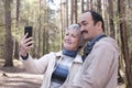Elderly interracial couple in a spring forest park, taking a selfie on your phone Royalty Free Stock Photo