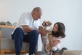 Elderly kind father with his beautiful teenage daughter playing with shih tzu puppy dog at home. Cute Caucasian family having fun Royalty Free Stock Photo