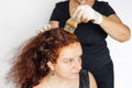 Elderly lady behind woman coloring hair in red with brush in hands with latex gloves on, White background. Hair coloring