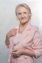 An elderly lady. Happy mature woman wearing pink suit, smiling, looking at the camera, on a light studio background. Concept again Royalty Free Stock Photo