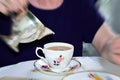 Elderly Lady Holding Chrome Milk Jug Over Vintage Bone China Cup. Focal Zoom Effect. Concept Of Mother`s Day. Concept Of Aging An