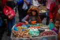 An elderly lady in an interesting hat sells vegetables at the local Indonesian authentic and colorful street market