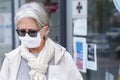 Elderly lady with mask and protective gloves leaves the pharmacy with medicines and instructions. Fear of coronavirus infection,