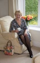 Elderly lady sitting in a chair drinking tea Royalty Free Stock Photo