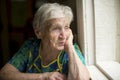 An elderly lady skeptically looking out the window. Sorrow. Royalty Free Stock Photo