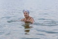 An elderly lady swims in a calm sea. Aged woman enjoying swimming in warm sea water at the resort