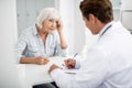 Elderly lady touching her head and looking at the practitioner