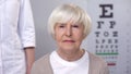 Elderly lady visiting friendly optometrist, checking vision, risk of cataract