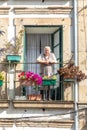 elderly lady watches the street from her balcony in the old town of Braga, Portugal