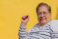 Elderly Latin American woman wearing glasses smiling looking at camera against a yellow background Royalty Free Stock Photo