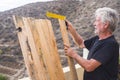 Elderly lifestyle at home with senior old caucasian man do  wooden hand work outdoor in the terrace - diy concept with retired Royalty Free Stock Photo