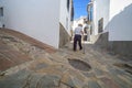 Elderly local man climbing slope narrow street of Comares, Malaga, Spain