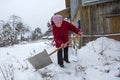 Elderly lone woman cleans the snow near his rural home. Royalty Free Stock Photo