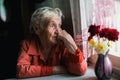 Elderly lone woman looks sadly out the window. Royalty Free Stock Photo