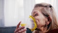 Elderly lonely woman using oxygen mask at home. Treatment of allergy or lung disease.