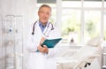 Elderly male doctor filling out medical forms in medical office Royalty Free Stock Photo