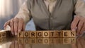Elderly male making word forgotten of wooden cubes on table, dementia disorder Royalty Free Stock Photo