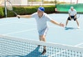 Elderly male player serving ball during training tennis in court outdoors Royalty Free Stock Photo