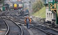 Elderly male volunteer at the Swanage steam railway walking on the tracks by the signal box at Swanage station, Dorset, UK