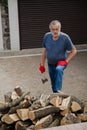 Elderly man with ax stands in front of pile of firewood Royalty Free Stock Photo